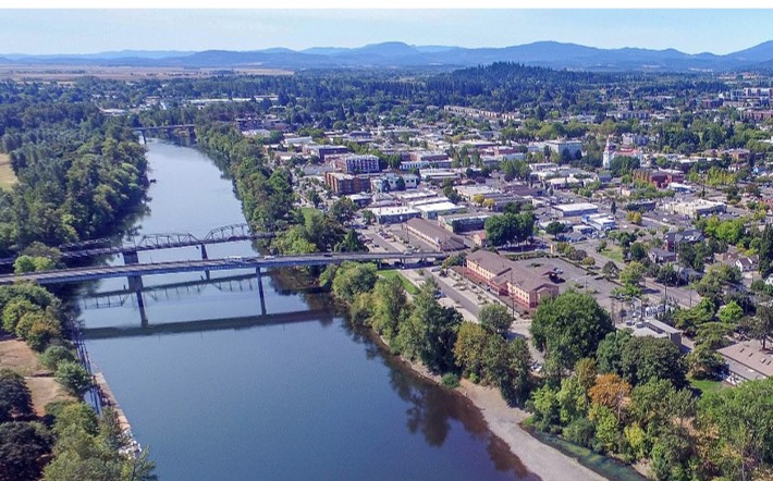 Aerial photograph of Corvallis, Oregon, overlooking the Willamette River with two bridges crossing the river into town and hills in the background.